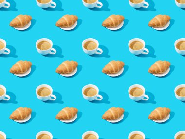 Taze kruvasanlar tabakta ve kahve mavi, kusursuz arka plan deseninde.