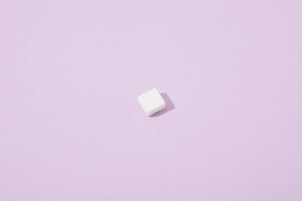 lump sugar cube on violet background with copy space