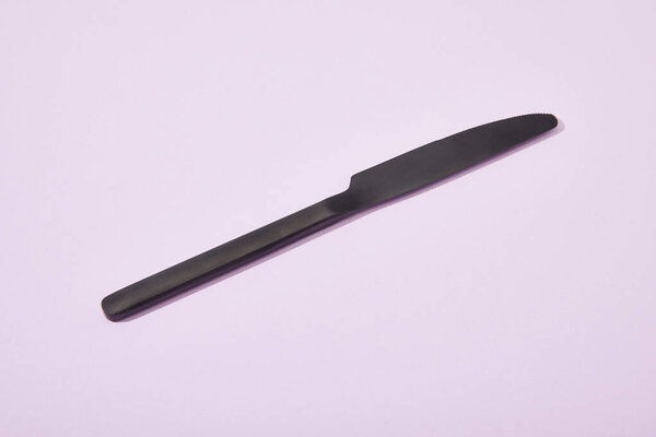 metal shiny black knife on violet background