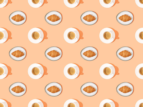 top view of fresh croissants on plates and coffee on orange, seamless background pattern