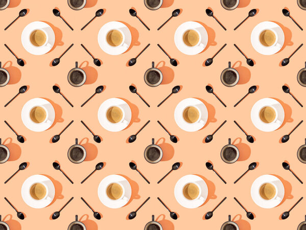 top view of cups of fresh coffee on plates and spoons on orange, seamless background pattern