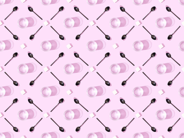 top view of lump sugar with black spoons and water on violet, seamless background pattern