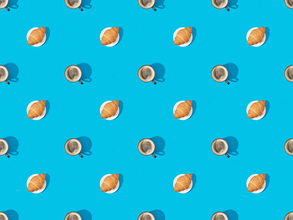 top view of croissants on plates and coffee on blue, seamless background pattern