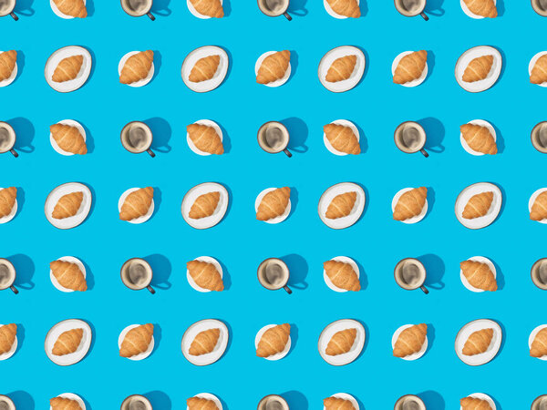 top view of croissants on plates and coffee on blue, seamless background pattern