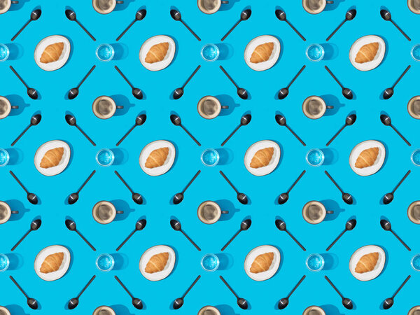 top view of spoons, croissants on plates, water and coffee on blue, seamless background pattern