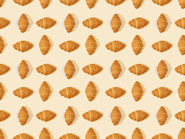 top view of fresh croissants on beige, seamless background pattern