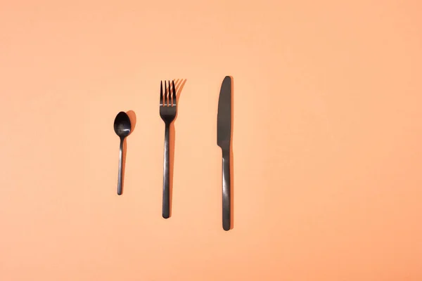 Top view of metal shiny black fork, spoon and knife on orange background — Stock Image Top View Metal Shiny Black Fork Spoon Knife Orange Background Royalty Free Stock Photos