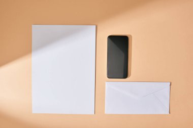 Üst sayfa kağıt, akıllı telefon ve bej arkaplan üzerindeki zarf görüntüsü