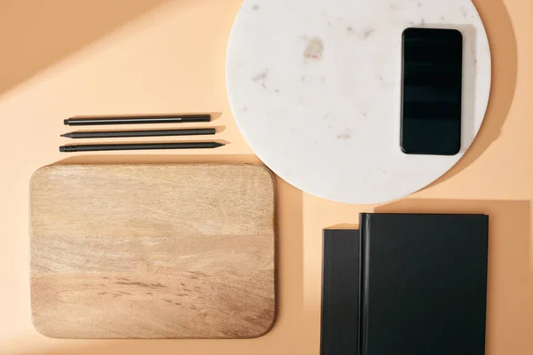 米色背景的木制和大理石板 智能手机 笔记本和钢笔的顶部视图 — 图库照片