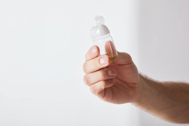Gri arka planda el dezenfektanı tutan adamın kırpılmış görüntüsü