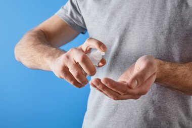 Mavi şişede jel el dezenfektanı kullanan bir adam görüntüsü.