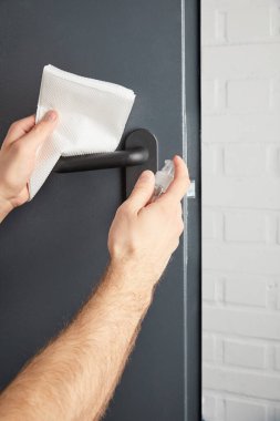 partial view of man disinfecting metal door handle with antiseptic and napkin clipart