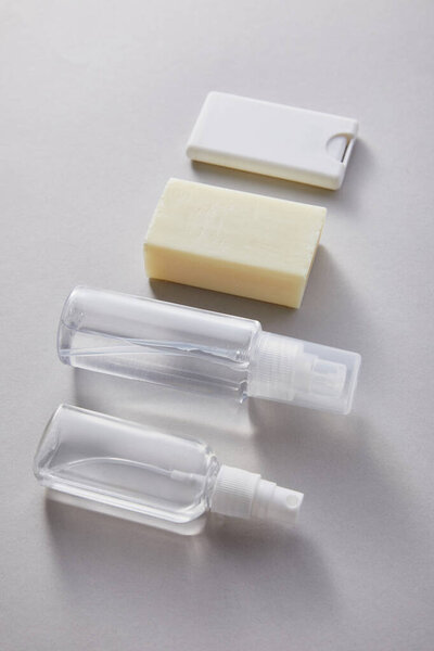 flat lay with hand sanitizer in spray bottles and antibacterial soap on grey background