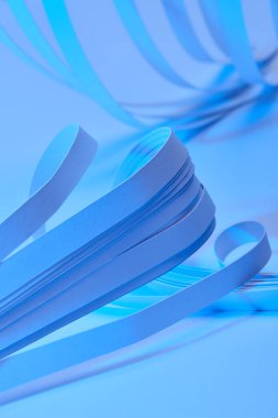 close up view of curved paper stripes on neon blue background clipart