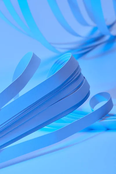 Nahaufnahme Von Gebogenen Papierstreifen Auf Neonblauem Hintergrund — Stockfoto