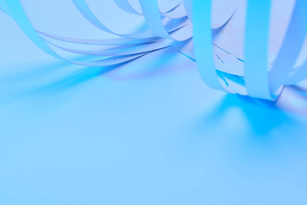 close up view of curved paper stripes on neon blue background