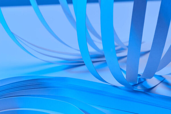 close up view of paper stripes on neon blue background