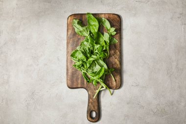 Top view of cutting board with basil leaves on grey background clipart