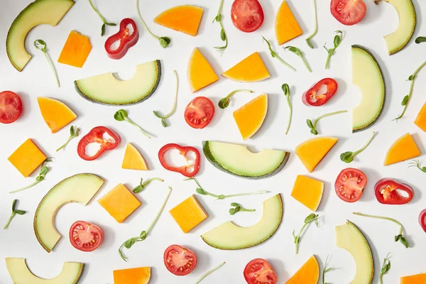 Flat lay with microgreens, cut vegetables and avocado slices on white background