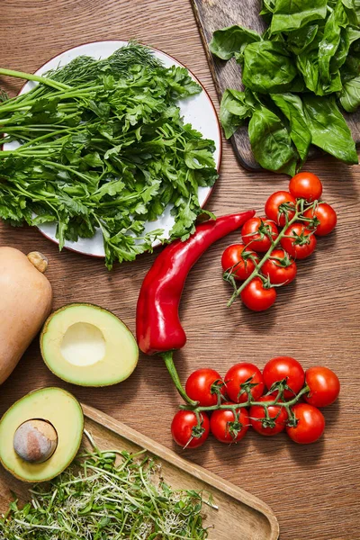 Top view of vegetables, avocado halves, greenery, microgreens and basil leaves on cutting boards on wooden background — Stock Image Top View Vegetables Avocado Halves Greenery Microgreens Basil Leaves Cutting Stock Image