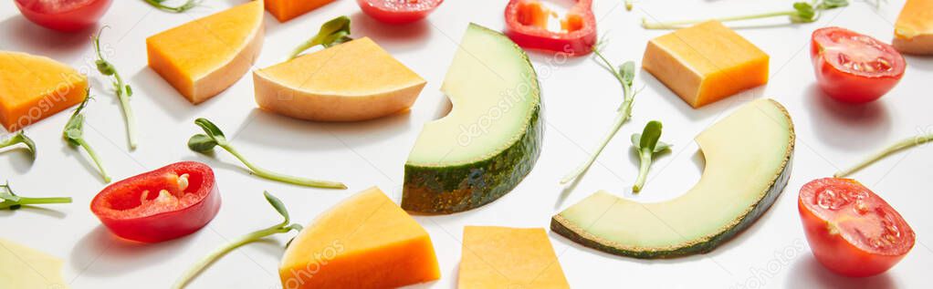 High angle view of microgreens, cut fresh vegetables and ripe avocado slices on white background, panoramic shot