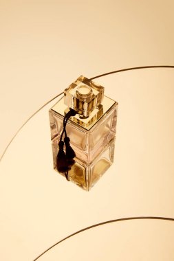 Yuvarlak bej ayna yüzeyinde yüksek açılı parfüm şişesi manzarası