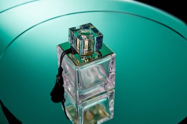 Koyu yeşil ayna yüzeyinde yansımalı mor parfüm şişesi.