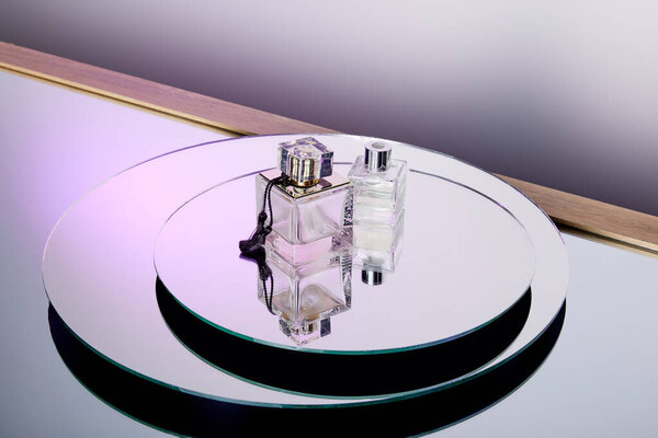 High angle view of luxury purple perfume bottles on round mirror surface