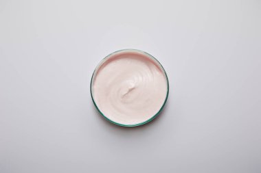 Gri arka planda pembe kozmetik kremi olan laboratuvar vitrininin üst görüntüsü