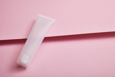 Pembe yapılandırılmış arka planda boş plastik kozmetik krem tüpünün yüksek açılı görüntüsü