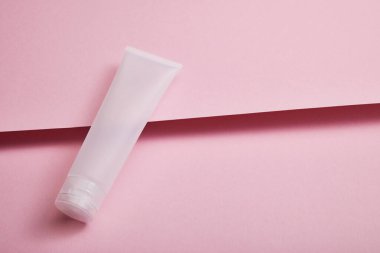 High angle view of empty plastic cosmetic cream tube on pink structured background clipart