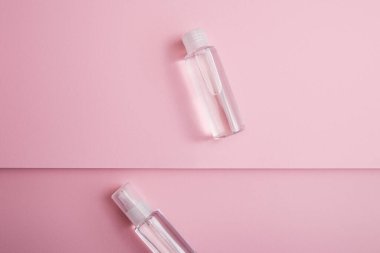 Top view of transparent hand sanitizer in bottle and spray with liquid on pink background clipart
