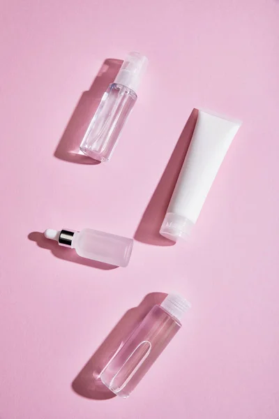 ピンクの背景に液体とクリームチューブ 化粧品ボトル スプレーや血清ボトルのトップビュー — ストック写真