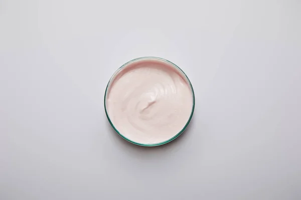 研究室用ガラス製品のトップビューとピンクの化粧品クリームグレーの背景 — ストック写真