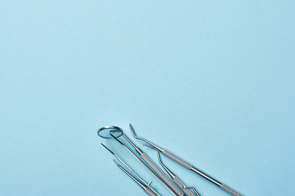 High angle view of metal professional dental instruments on blue background