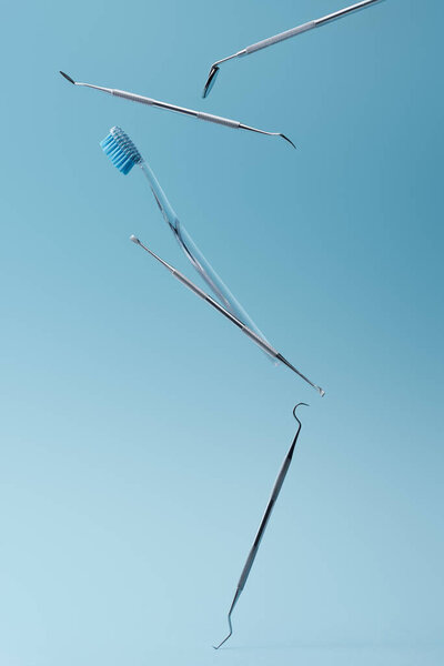 Dental professional instruments and toothbrush levitating on blue background