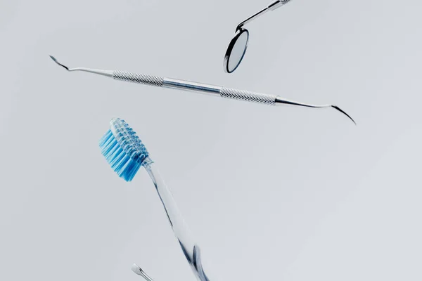 带蓝色刚毛的牙科器械和牙刷 在灰色背景下悬浮 — 图库照片