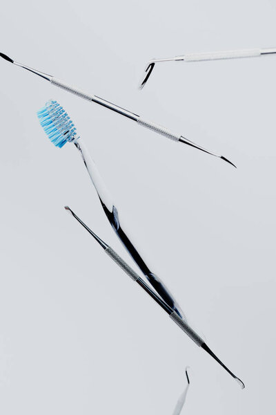 Dental metal instruments and toothbrush with blue bristles isolated on grey background