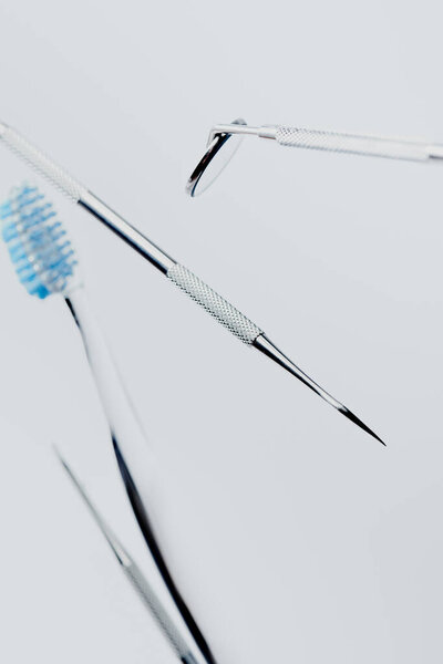 Selective focus of dental professional equipment and toothbrush with blue bristles isolated on grey background