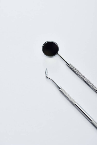 High angle view of dental mirror and dental carver for teeth examination on grey background