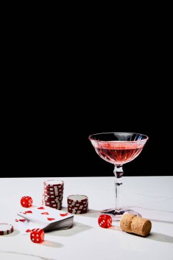 Kağıt destesi, bir bardak kokteyl, zar, kumarhane jetonları ve mantar siyah üzerine izole edilmiş beyaz yüzey