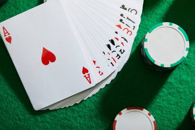 Yeşil arka planda kumarhane çipleri olan kart paketlerinin üst görünümü