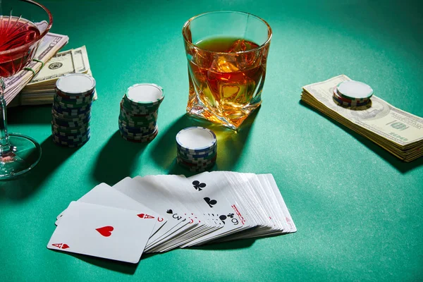 お金とコニャックとカクテルのグラスの高い角度ビュー カジノのチップと緑のトランプ — ストック写真