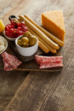 Tahtadaki ahşap zemin üzerinde antipasto içerikli ekmek çubuklarının yüksek açılı görünümü