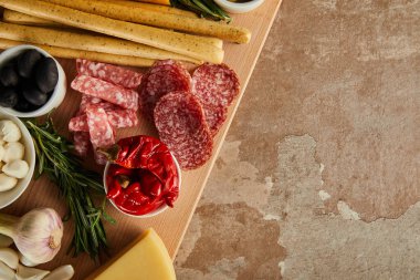 Kahverengi arkaplanda antipasto içeriği olan tahtaya üst görünüm