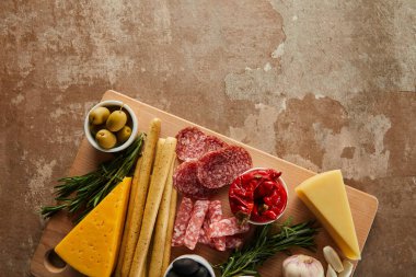 Ekmek çubukları, peynir, salam dilimleri ve antipasto malzemelerinin en üst görünümü kahverengi.