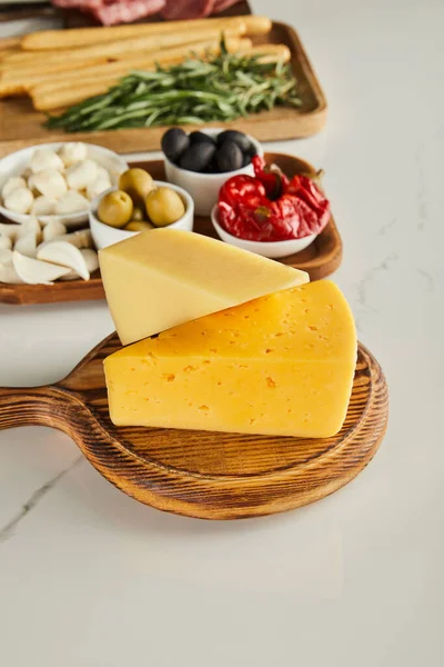 白にチーズとアンティパスト成分とボードの選択的な焦点 — ストック写真