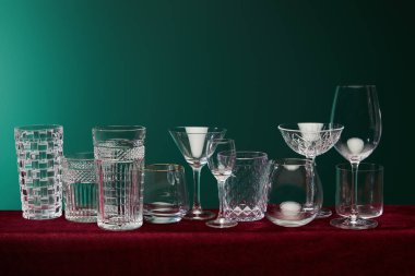 Eski moda bardaklar, kokteyl bardakları, şampanya bardakları, shot bardakları, viski bardakları, Collins bardakları, brendi bardakları, konyak balonları ve Collins bardakları yeşil arka planda.