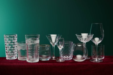 set of glasses: old fashioned glass, cocktail glass, champagne flute, shot glass, highball glass, collins glass, brandy glass, cognac balloon and collins glass on green background clipart