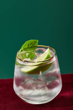 close up view of cold mojito with mint in glass with golden rim isolated on green  clipart